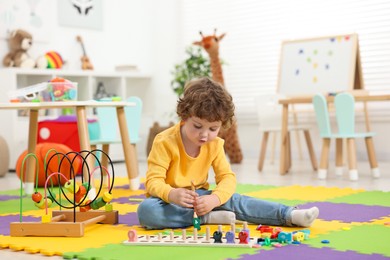 Cute little boy playing with math game Fishing for Numbers on puzzle mat in kindergarten