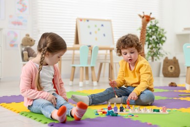 Photo of Cute little children playing with math game Fishing for Numbers on puzzle mat in kindergarten