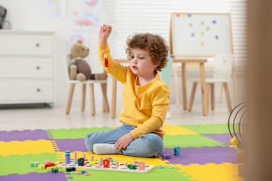 Cute little boy playing with math game Fishing for Numbers on puzzle mat in kindergarten