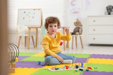 Cute little boy playing with math game Fishing for Numbers on puzzle mat in kindergarten