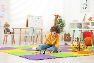 Photo of Cute little boy playing with math game Fishing for Numbers on puzzle mat in kindergarten