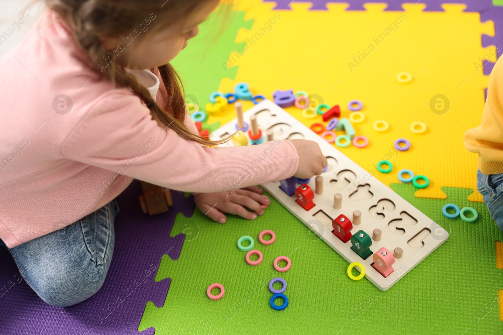 Photo of Little girl playing with game Fishing for Numbers on puzzle mat, closeup. Kindergarten activities for learning mathematics