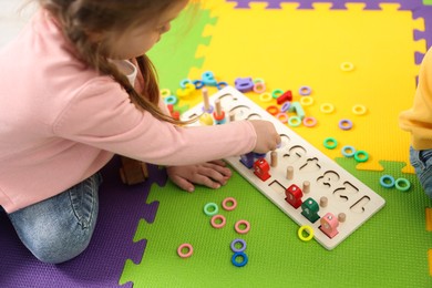 Little girl playing with game Fishing for Numbers on puzzle mat, closeup. Kindergarten activities for learning mathematics