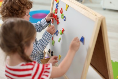 Photo of Little children learning alphabet with magnetic letters on board in kindergarten