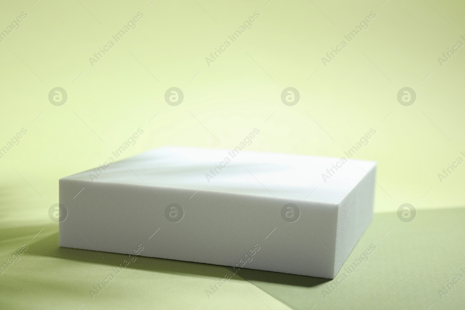 Photo of Presentation of product. Podium, paper and shadows on light green background. Space for text\
