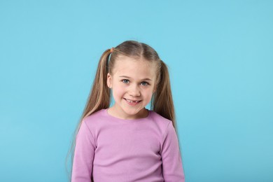 Photo of Portrait of cute little girl on light blue background