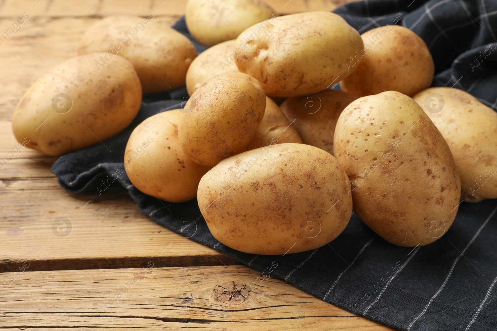 Photo of Many fresh potatoes on wooden table, closeup