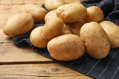 Many fresh potatoes on wooden table, closeup