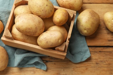 Many fresh potatoes in crate on wooden table, above view