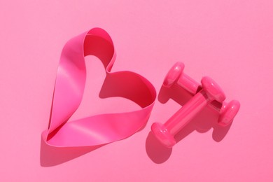 Photo of Dumbbells and fitness elastic band on pink background, flat lay