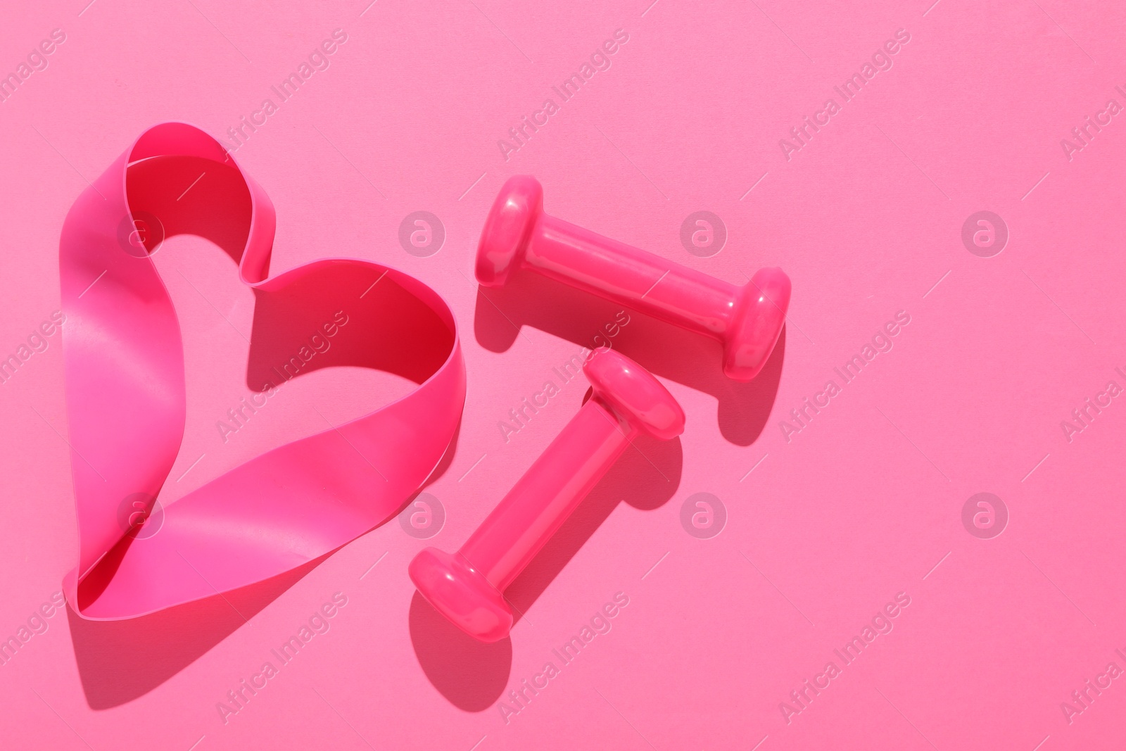 Photo of Dumbbells and fitness elastic band on pink background, flat lay