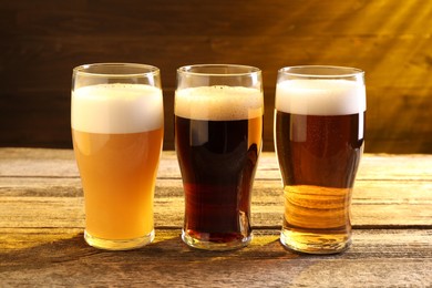 Glasses with different types of beer on wooden table