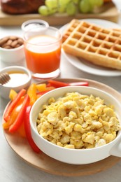 Photo of Tasty breakfast. Scrambled eggs in bowl, bell pepper and other food on light table, closeup