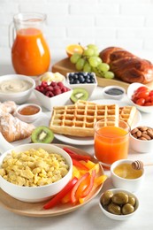 Tasty breakfast. Scrambled eggs in bowl, bell pepper, olives, honey and other food on light table