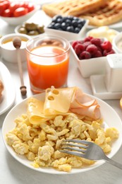 Tasty breakfast. Scrambled eggs, ham, cheese and other food served on light wooden table, closeup