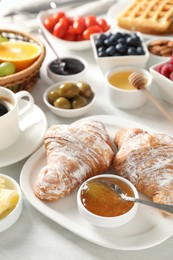 Tasty breakfast. Croissants, jam and other food on light table, closeup