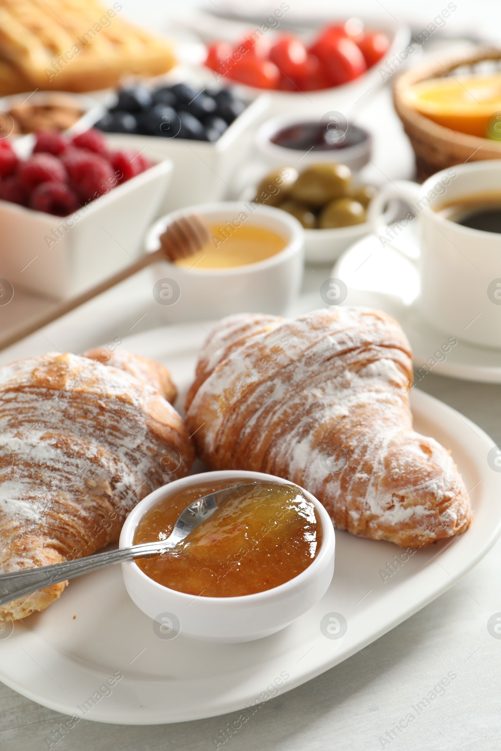 Photo of Tasty breakfast. Croissants, jam and other food on light table, closeup