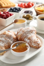 Photo of Tasty breakfast. Croissants, jam and other food on light table, closeup