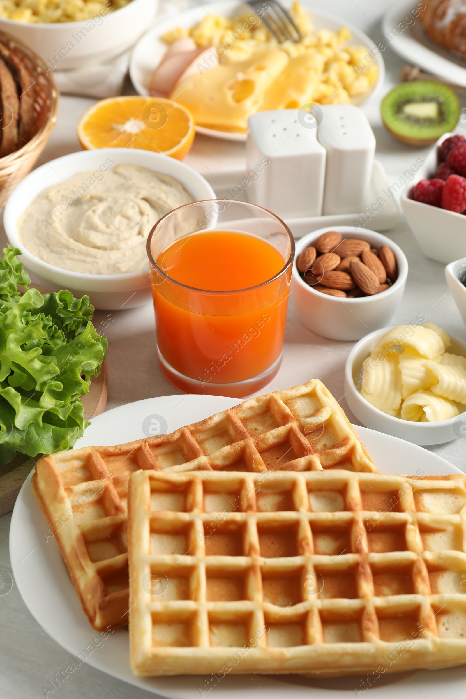 Photo of Tasty breakfast. Belgian waffles and other food on light table, closeup