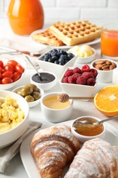 Photo of Tasty breakfast. Croissants, jam and other food on light table, closeup