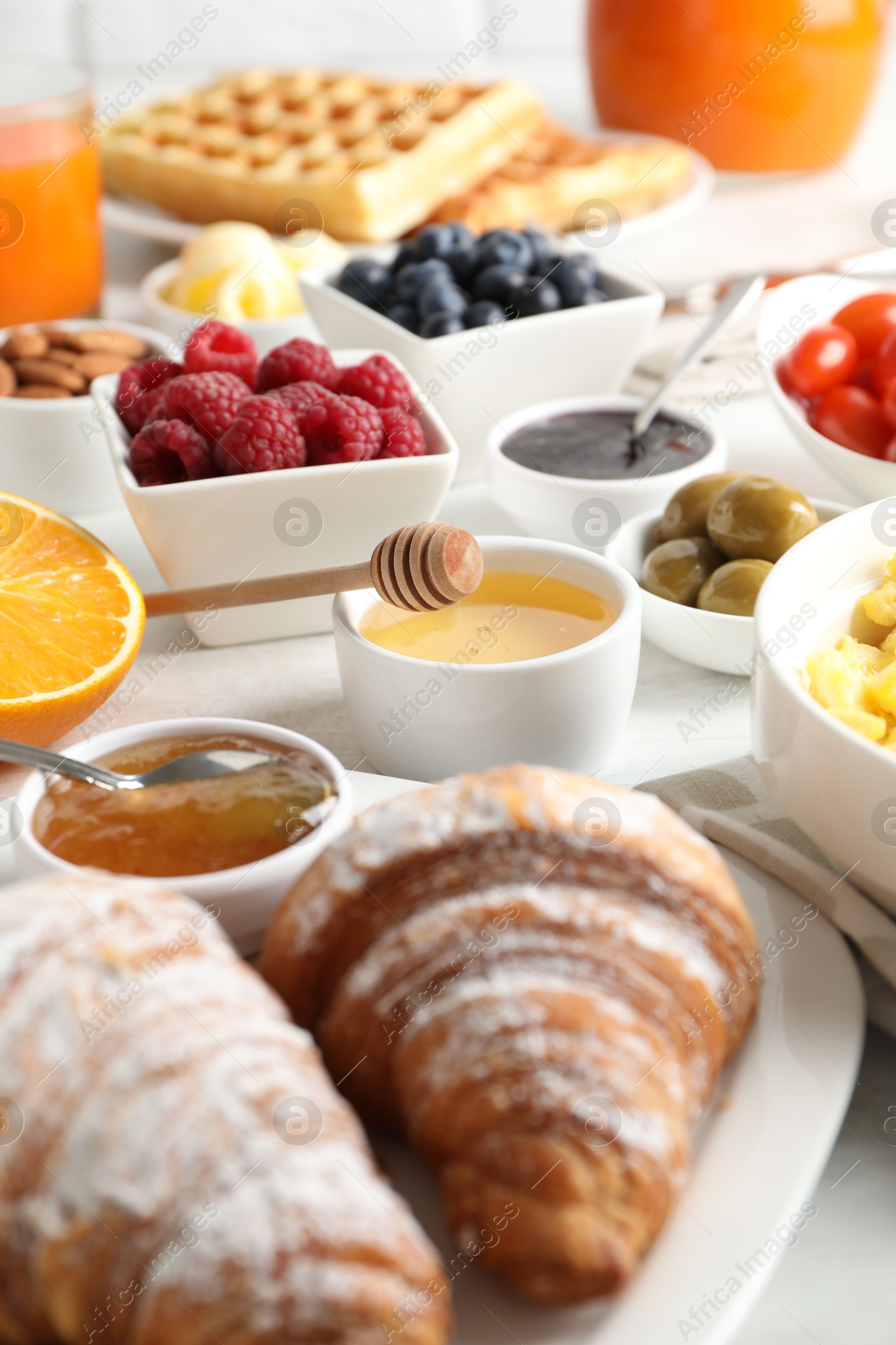 Photo of Tasty breakfast. Croissants, jam and other food on light table, closeup