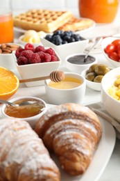 Tasty breakfast. Croissants, jam and other food on light table, closeup