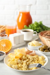 Photo of Tasty breakfast. Scrambled eggs, ham, cheese and other food served on light table, closeup