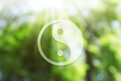 Yin and yang symbol against blurred green trees