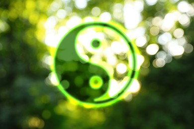 Image of Yin and yang symbol against blurred green trees