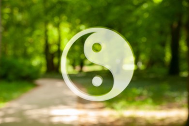 Image of Yin and yang symbol against blurred view of green park