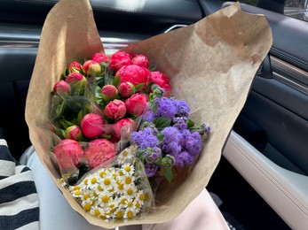 Photo of Bouquets of beautiful flowers in car, closeup