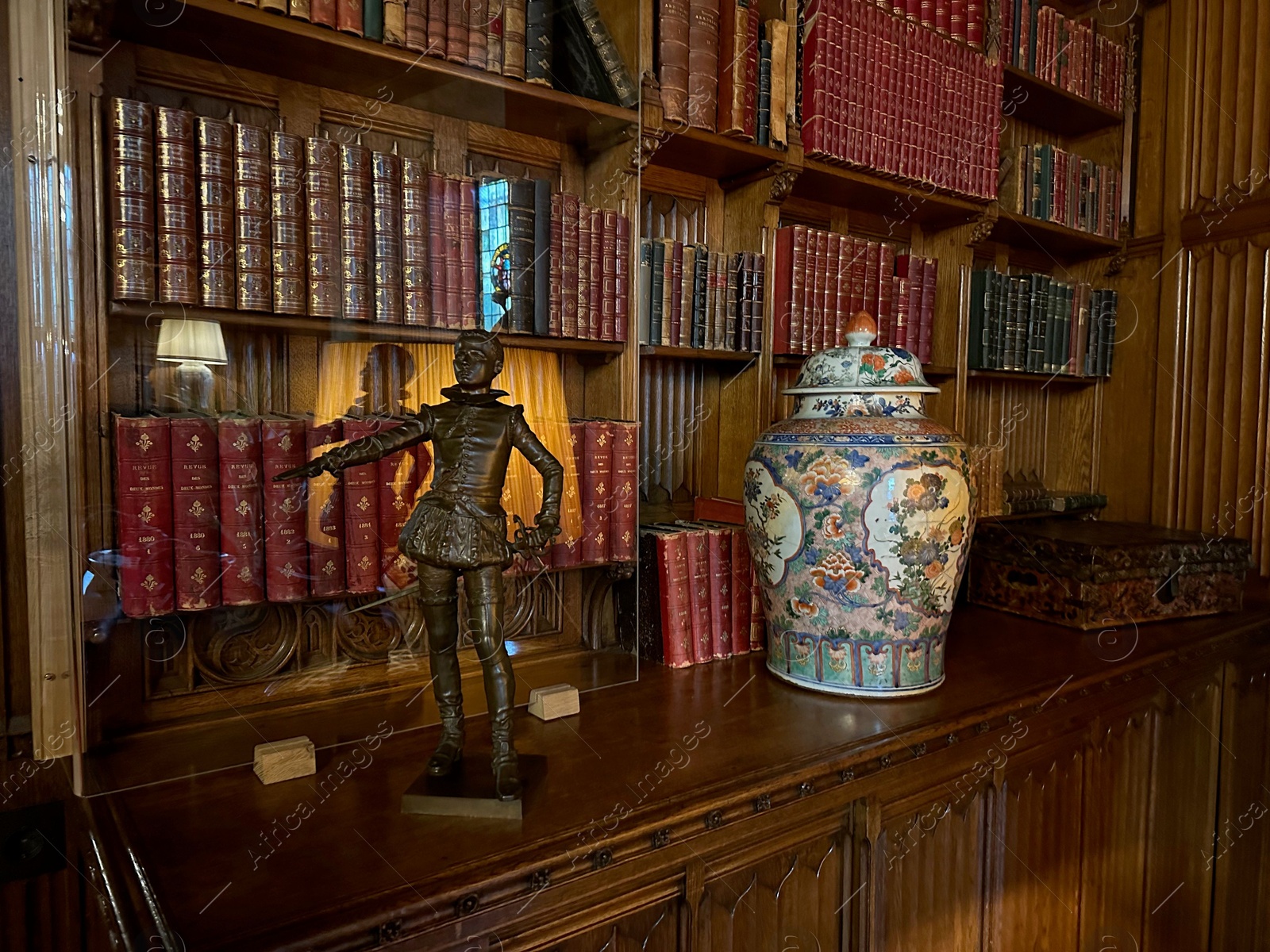 Photo of Utrecht, Netherlands - June 17, 2024: Bookcase with old books, antique vase and bronze statue of Henry IV as child in De Haar castle