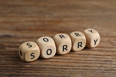 Word Sorry of small cubes with letters on wooden table, closeup