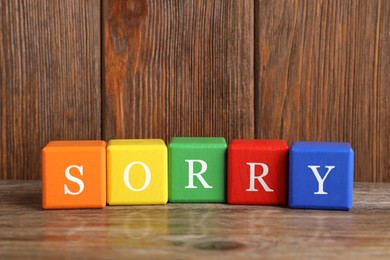Image of Word Sorry of colorful cubes with letters on wooden table
