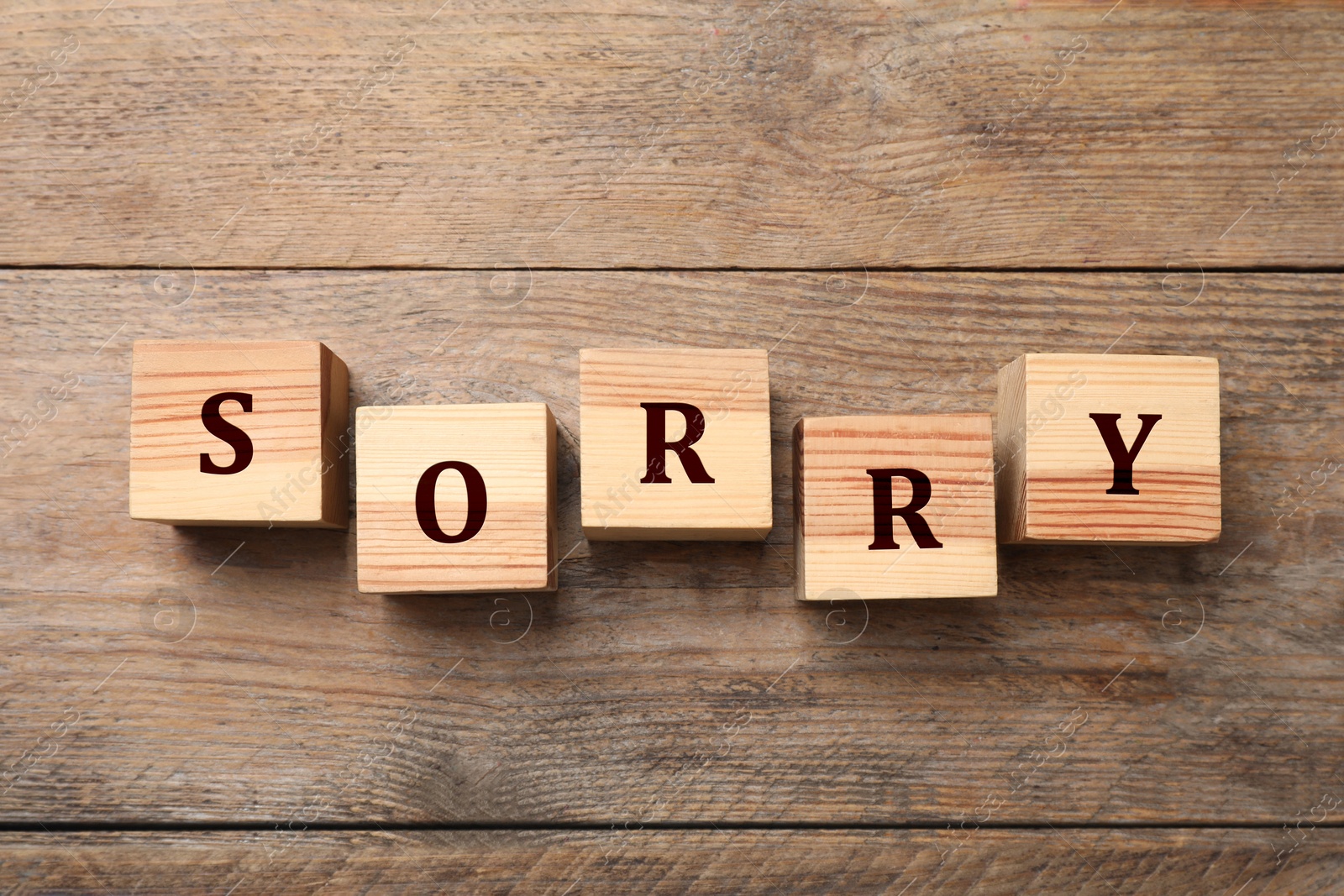 Image of Word Sorry of cubes with letters on wooden table, top view