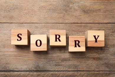 Word Sorry of cubes with letters on wooden table, top view