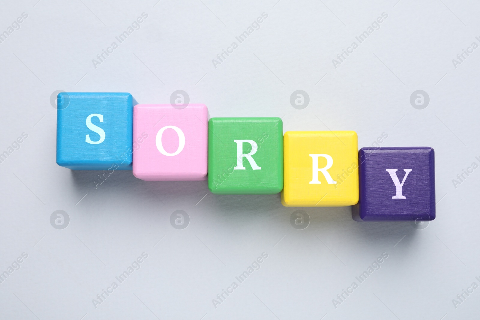 Image of Word Sorry of colorful cubes with letters on light table, top view