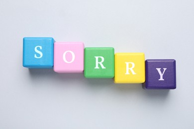 Word Sorry of colorful cubes with letters on light table, top view