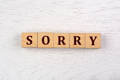 Image of Word Sorry of cubes with letters on white wooden table, top view