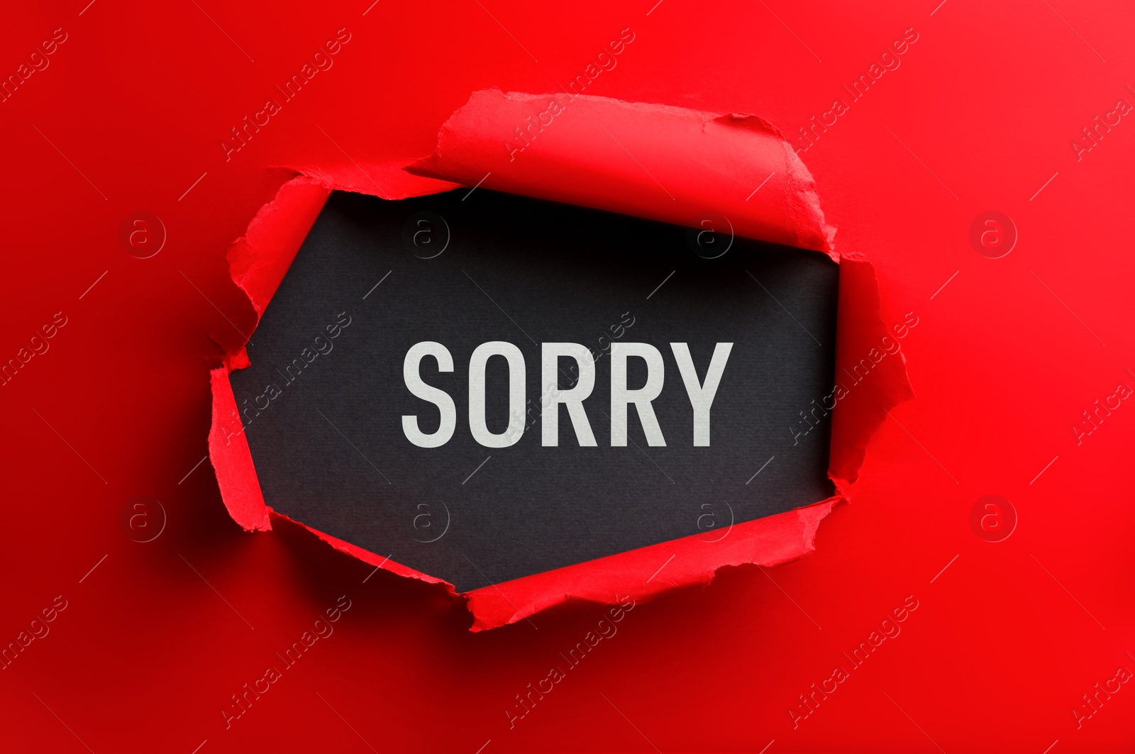 Image of Word Sorry on black background, view through torn red paper