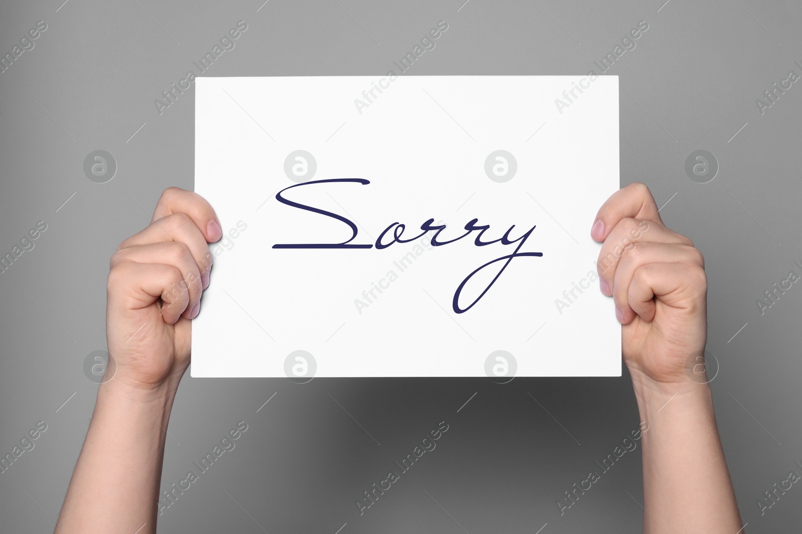 Image of Woman holding sheet of paper with word Sorry on grey background, closeup