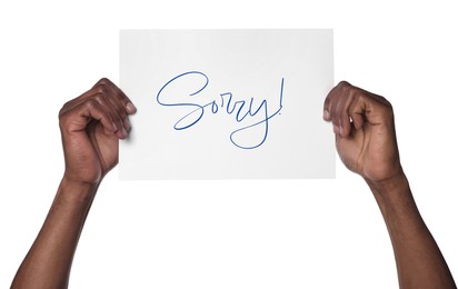Man holding sheet of paper with word Sorry on white background, closeup