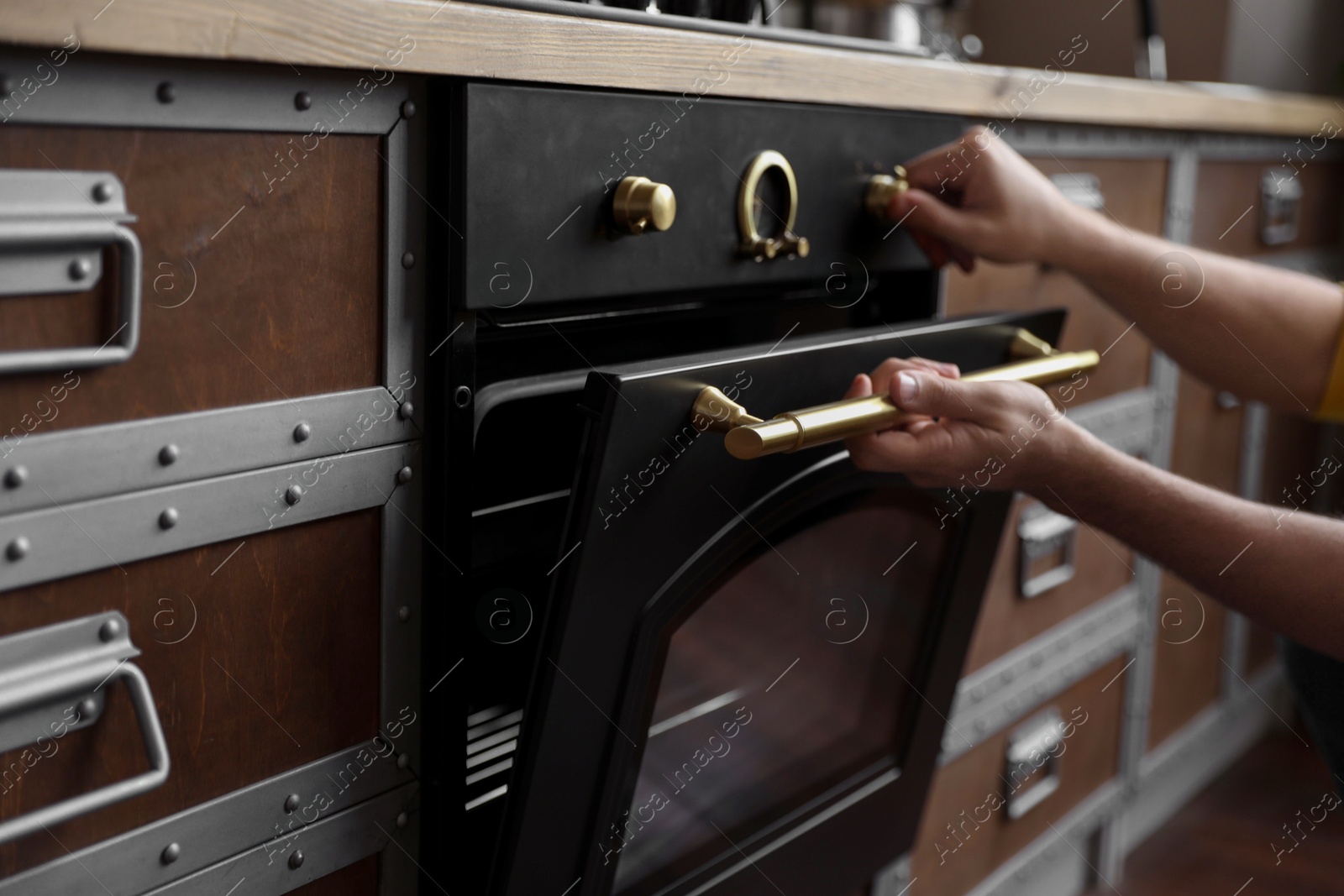 Photo of Man using modern oven in kitchen, closeup