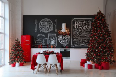Photo of Stylish kitchen interior with festive table and decorated Christmas trees