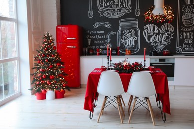 Stylish kitchen interior with festive table and decorated Christmas tree
