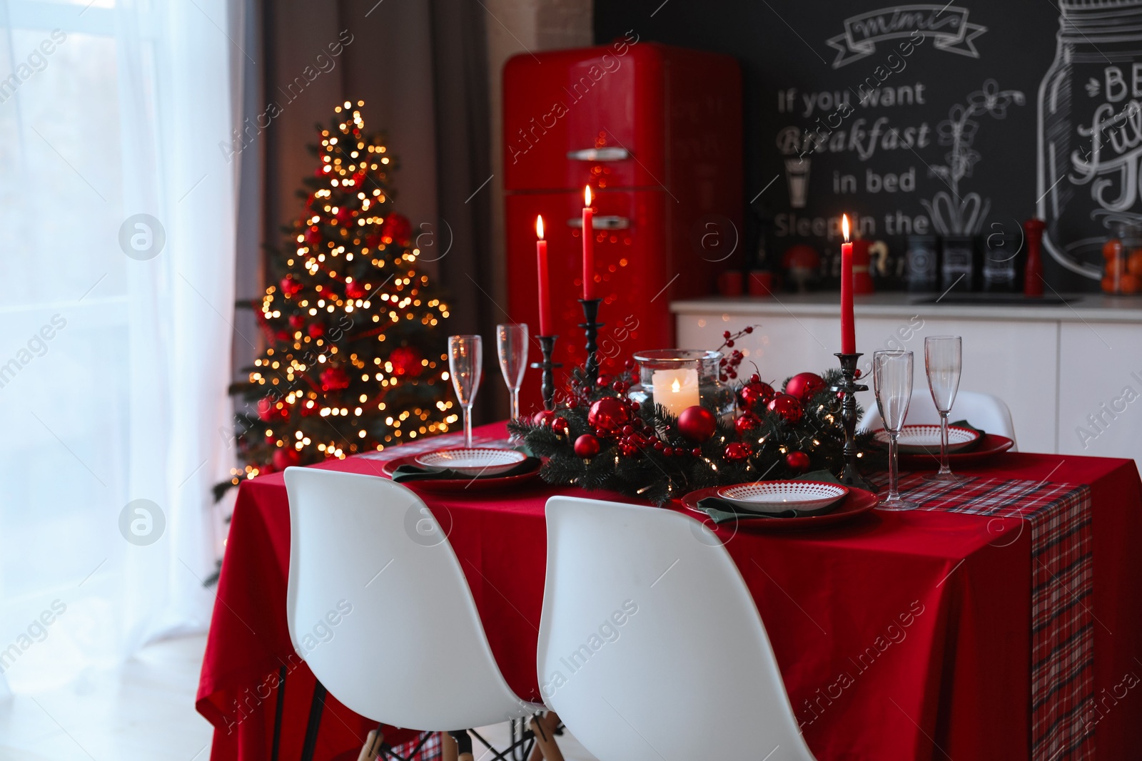 Photo of Table served for festive dinner and Christmas tree in stylish kitchen interior