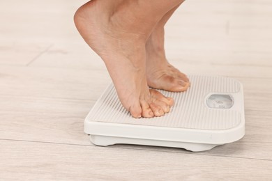 Photo of Woman standing on floor scales indoors, closeup