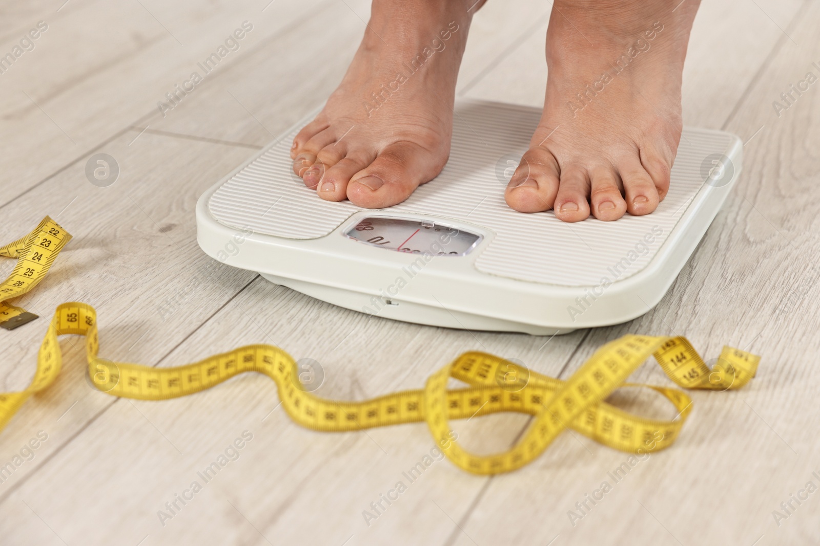 Photo of Woman standing on floor scales indoors, closeup