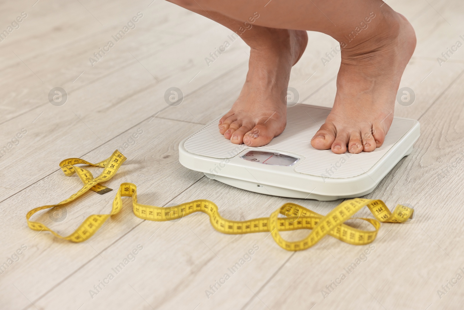 Photo of Woman standing on floor scales indoors, closeup