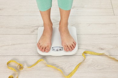 Woman standing on floor scales indoors, above view